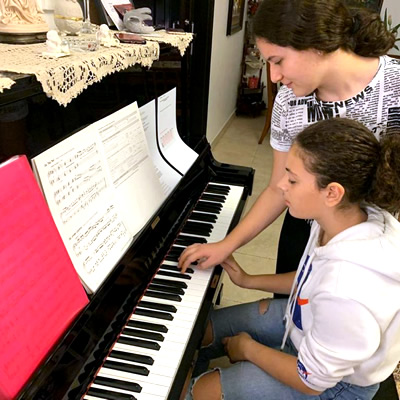 A student taking piano lesson from an Elite Music teacher